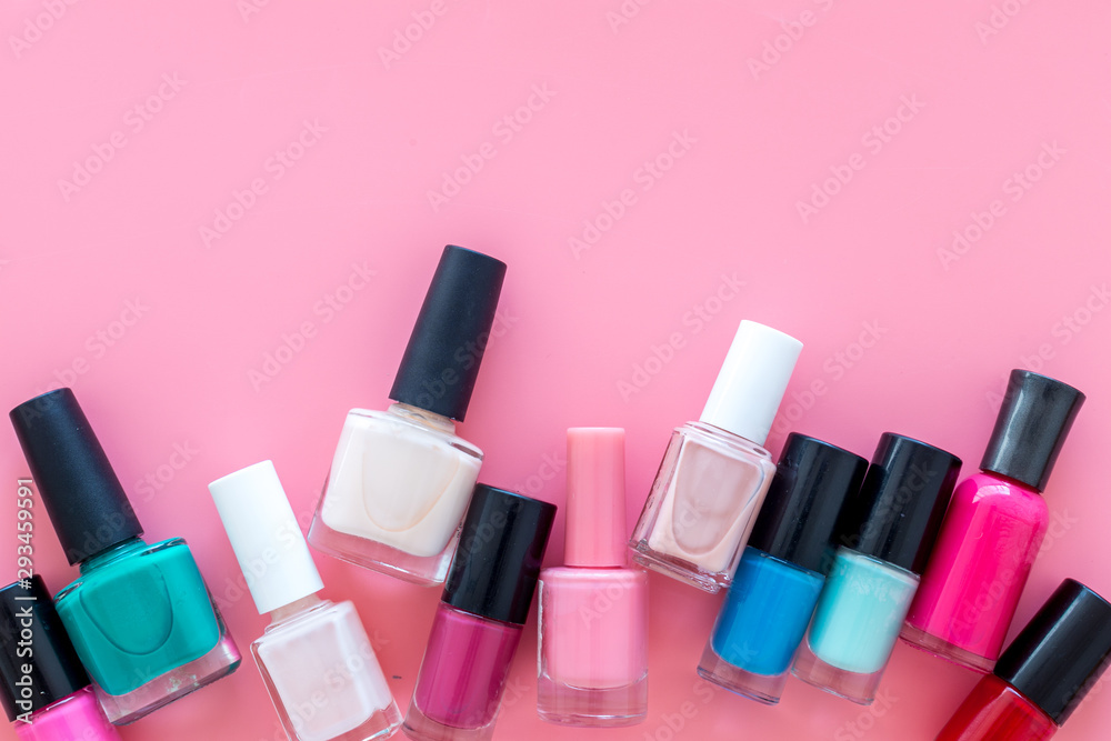 Choose nail polish. Polish bottels on pink background top view copy space - obrazy, fototapety, plakaty 