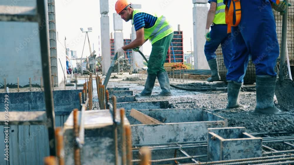 Builders work with concrete on construction site.