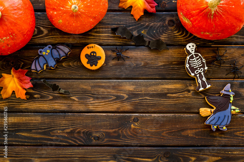 Halloween frame with pumpkins, paper bats and special cookies on dark wooden background top view space for text