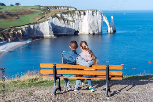 Couple in love sitting in front of the sea contemplating the beauty of the landscape