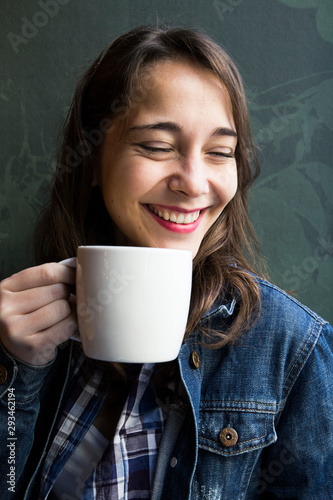 Young laughing woman in cafe with cup of coffee and looking sideways