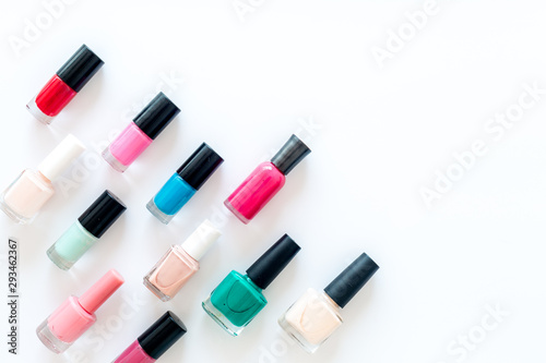 Nail polishes background on white table top view pattern copy space