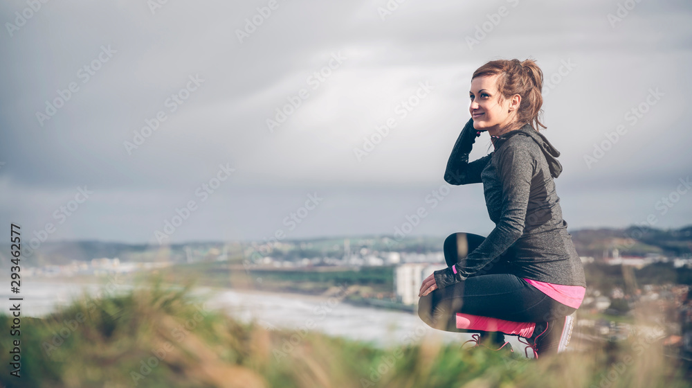 Sporty mid adult woman on cliff looking at sea