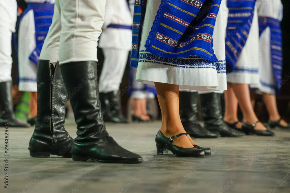 Close up of legs of young Romanian female and male dancers in traditional folkloric costume. Folklore of Romania