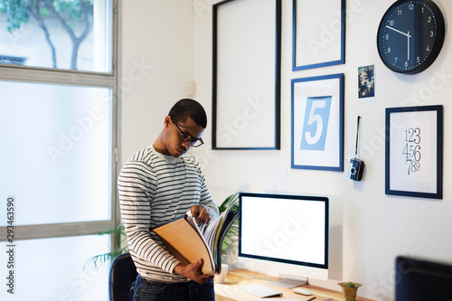 Young creative man with files in his home office photo