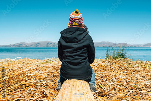 Peru, Puno, woman wearing chullo sitting on floating island in Lake Titicaca photo