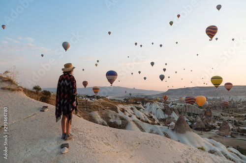 Young woman and hot air balloons in the evening, Goreme, Cappadocia, Turkey photo