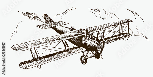 Historical biplane with aerial camera in front of large cumulus clouds