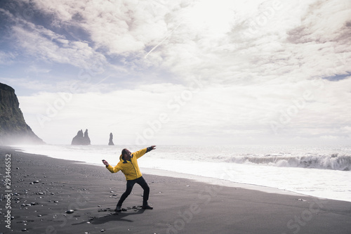 Mature man throwing a stone into the sea, on a lava beach in Iceland