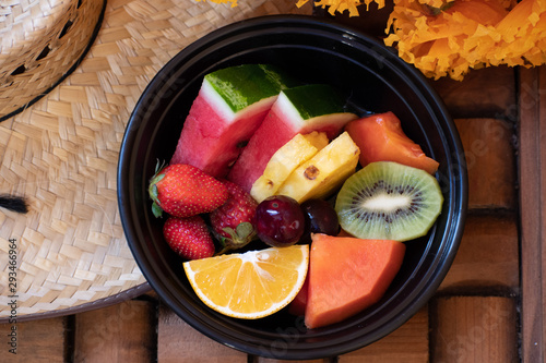 Variety colored fresh fruits cutted into the black bowl.