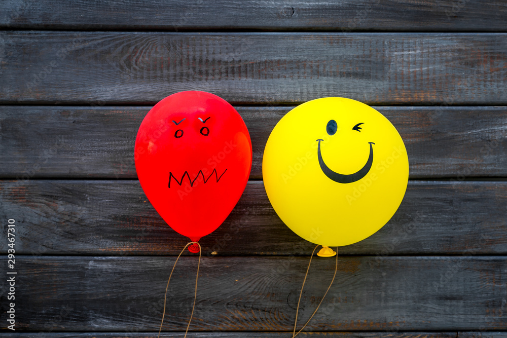 Naklejka Treat depression concept. Balloons with frustrated and smiling faces on dark wooden background top view