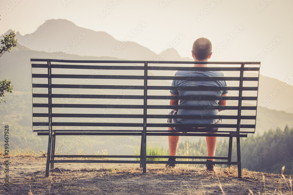 homme assis sur un banc devant un paysage Photos | Adobe Stock