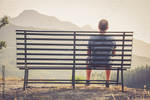 homme assis sur un banc devant un paysage photo