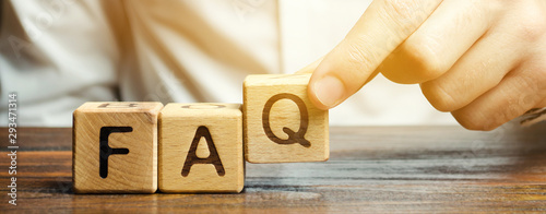 Businessman puts wooden blocks with the word FAQ (frequently asked questions). Collection of frequently asked questions on any topic and answers to them. Instructions and rules on Internet sites photo