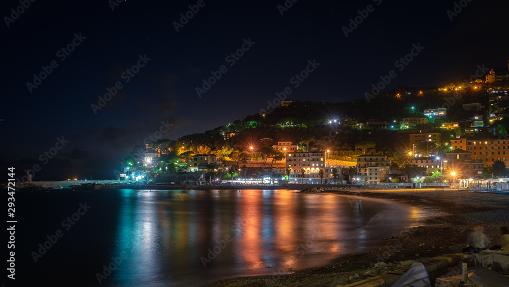Recco, Genoa, Italy. Wide view of the city of the Ligurian Riviera at night. In the foreground the reflections of the lights of the city on the sea.