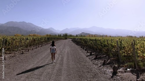 Young woman walking through winery in Mendoza, Argentina with aerial footage showcasing stunning landscapes photo