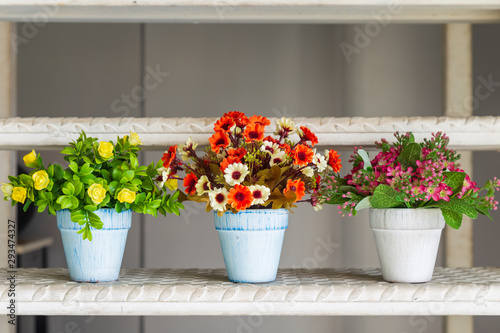 Beautiful artificial flowers in pot on steel stairs