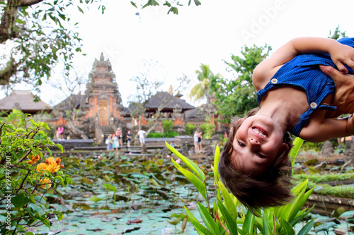 Portrait of a cute little kid with Pura Taman Saraswati temple on background, Ubud, Bali, Indonesia.