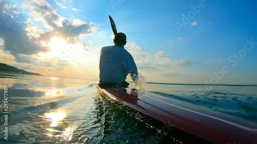 Backside view of a male boater navigating a canoe