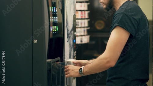 Young Man Drinking Coffee or Tea from Vending Machine
