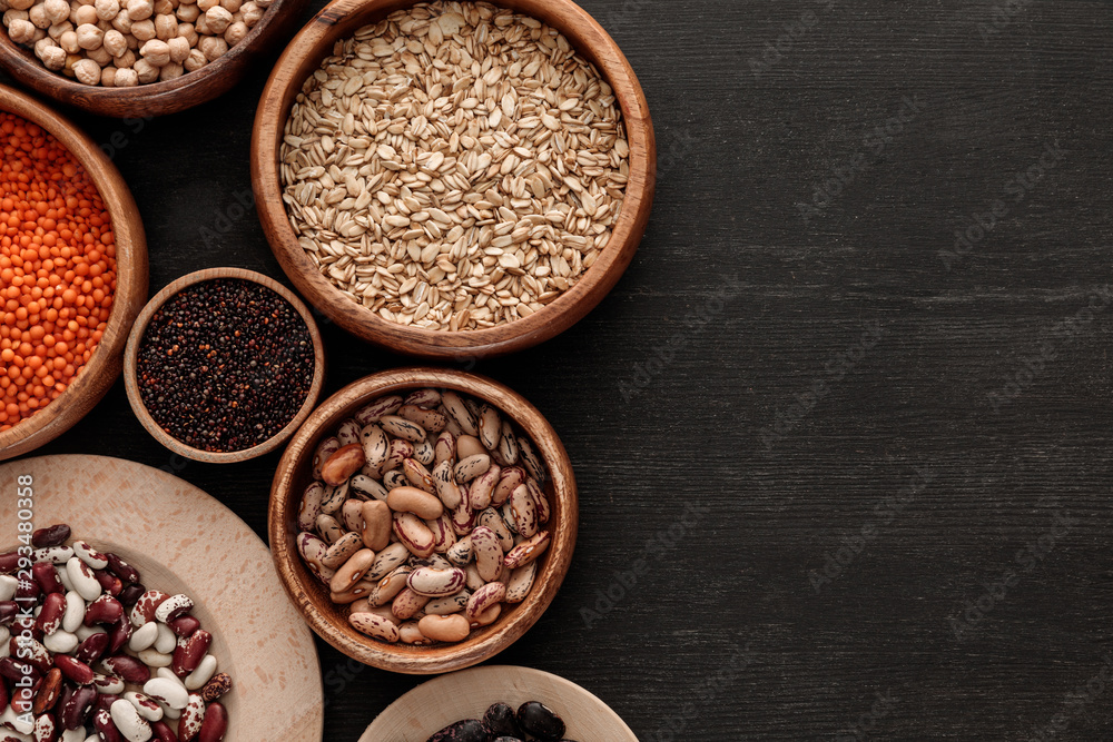 top view of brown bowls with raw beans, lentil, oatmeals and quinoa on dark wooden surface with copy space top view of brown bowls with raw beans, lentil, oatmeals and quinoa on dark wooden surface with copy space