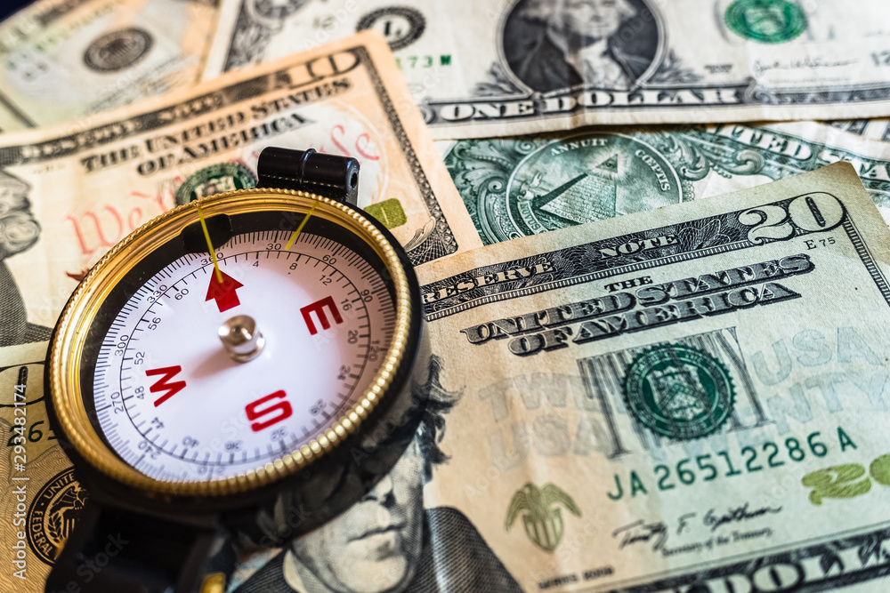 Close-up of a compass on dollar bills, guide for making smart investment decisions. Close-up of a compass on dollar bills, guide for making smart investment decisions.