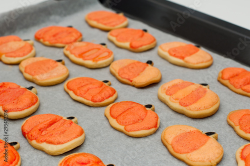 Homemade Halloween cookies decorated with icing on a tray. Orange pumpkins