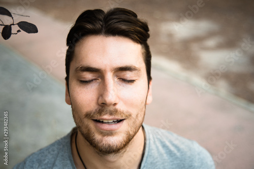 Young model man, close-up with eyes closed, inspiring to relax in nature.