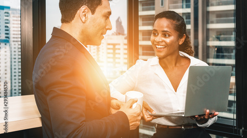 diverse business people having business conversation during coffee break time with laptop computer and cup of coffee at window corner in office photo