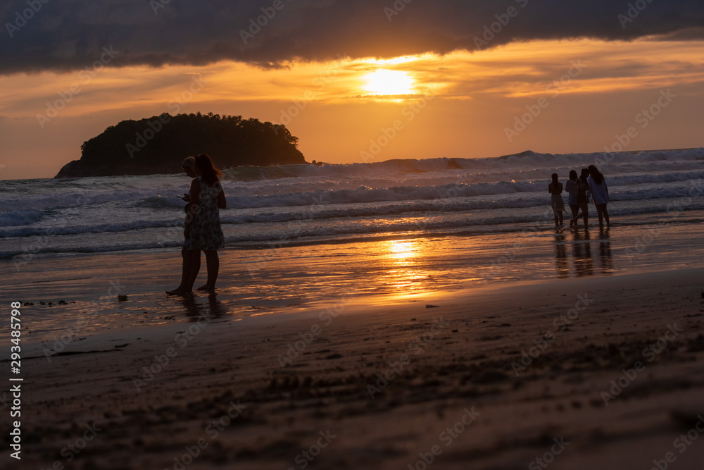 silhouettes of people on beach at sunset