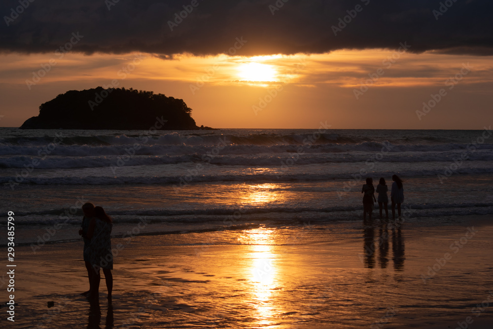 silhouettes of people on beach at sunset