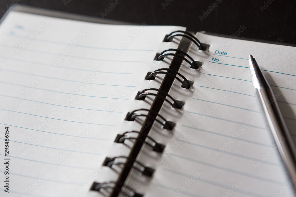 Selective focus of Pen, notebook, on black background and copy space Selective focus of Pen, notebook, on black background and copy space