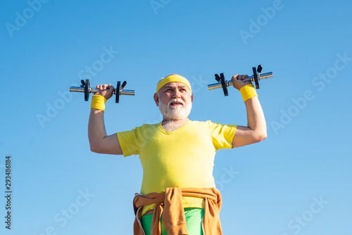 Old man holding his hands in front of him while lifting dumbbells. Grandfather exercising with dumbbell. Sport for senior man.