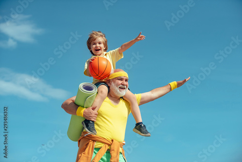 Like sports. Joyful old-aged man and cute little boy practicing sport and healthy lifestyle over sky background. Fathers day.