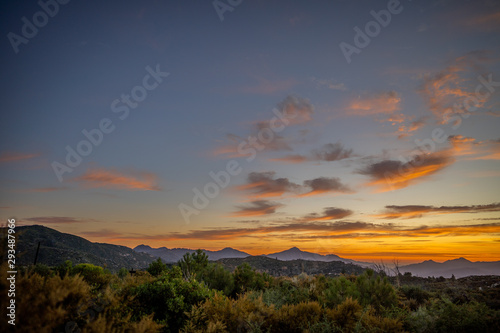 Scattered orange and purple clouds at sunset over mountain peaks