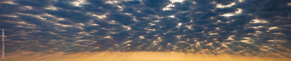 Panorama view of crepuscular ray of sunlight shines through the cloudy sky for background graphic design purpose