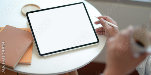 Top view of man holding blank screen tablet and drinking a cup of coffee
