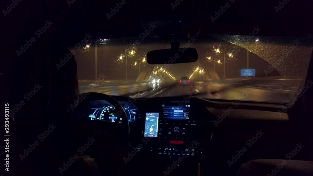 Chinese uber drives down highway in the rain at night. Rainy highway with professional driver in ride share service using app for navigation. Ride hailing service in China in the evening. Chinese uber drives down highway in the rain at night. Rainy highway with professional driver in ride share service using app for navigation. Ride hailing service in China in the evening.