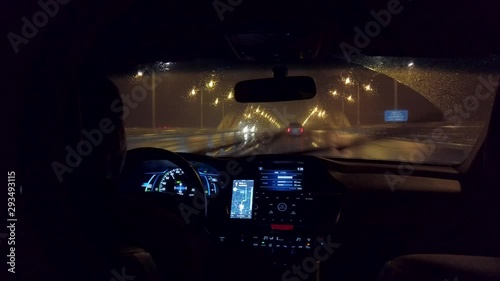 Chinese uber drives down highway in the rain at night. Rainy highway with professional driver in ride share service using app for navigation. Ride hailing service in China in the evening.