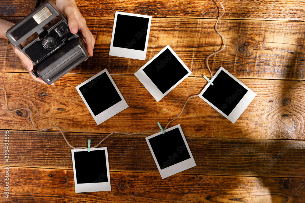 Top view on blank photographs and camera in hands on a wooden table. The concept of pleasant memories. Top view on blank photographs and camera in hands on a wooden table. The concept of pleasant memories.