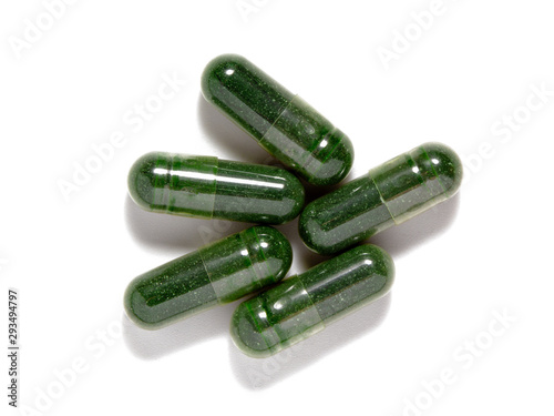Green chlorella powder capsules isolated on white background. Natural supplement pills, alternative medicine