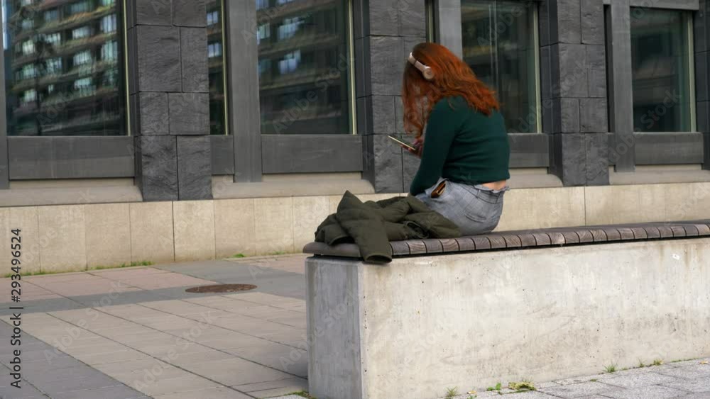 Red haired woman with headphones browsing phone Red haired woman with headphones browsing phone