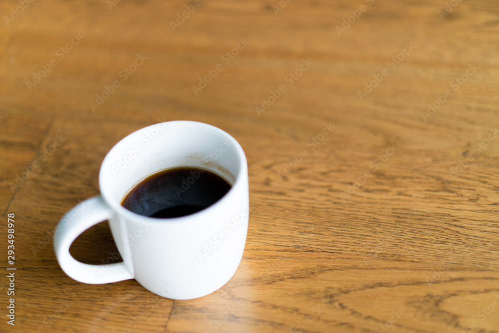 White ceramic coffee mug on the table in coffee bar with copy space. Coffee mug background. White ceramic coffee mug on the table in coffee bar with copy space. Coffee mug background.