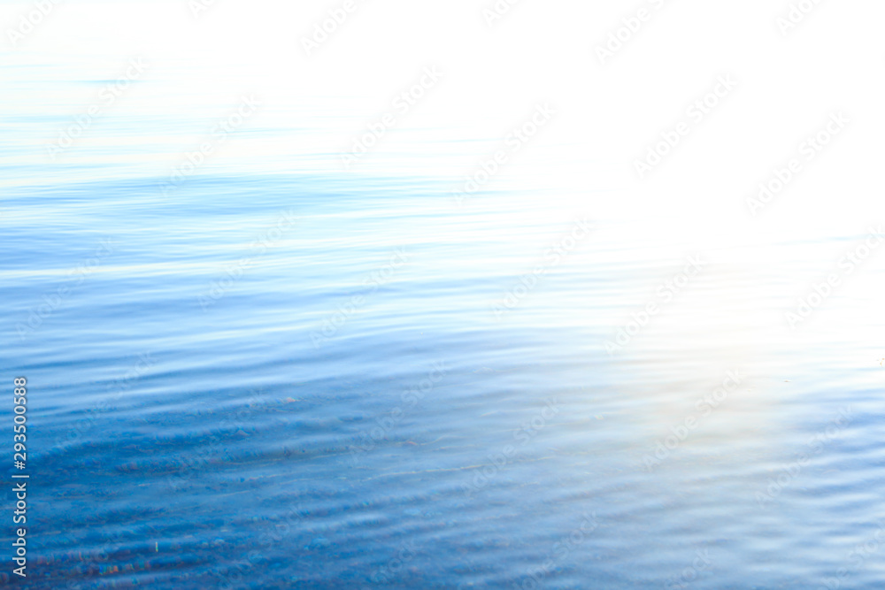 Naklejka premium Clear water texture in blue and orange. Background of the ocean and the sea backlit by the sun. Soft waves. Natural water