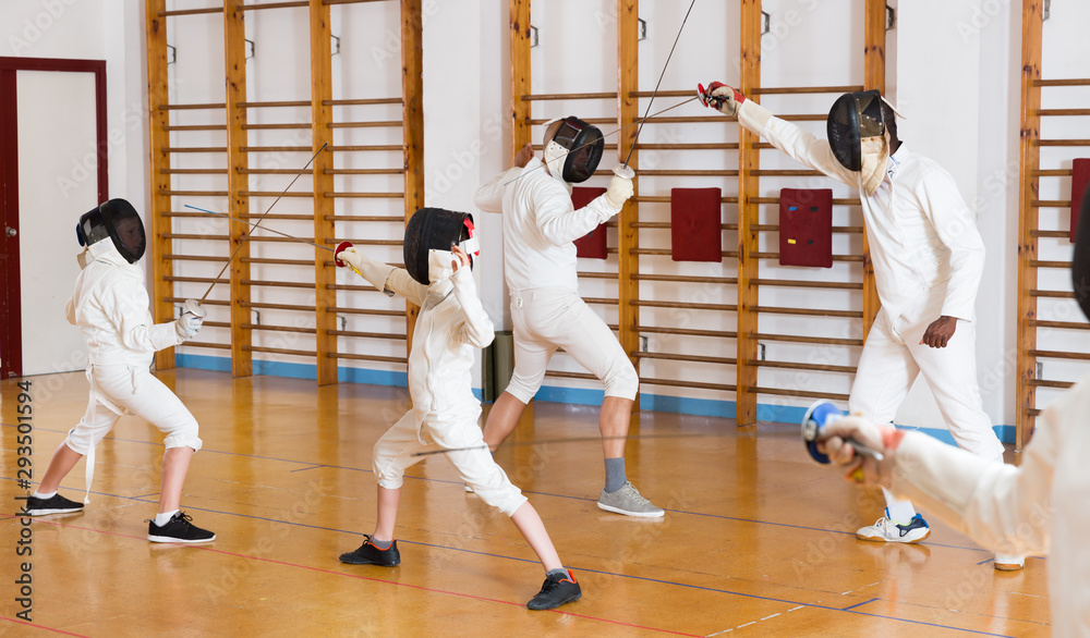 Adults and teens wearing fencing uniform practicing with foil