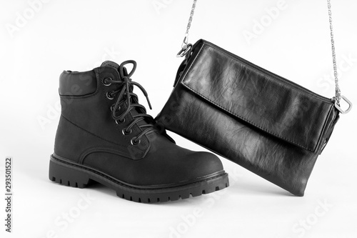 black heavy duty female boots and fashionable leather clutch on white background