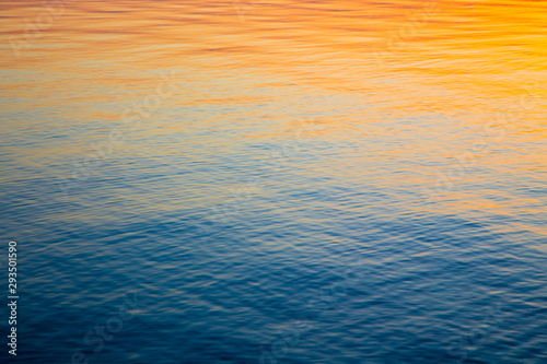 Clear water texture in blue and orange. Background of the ocean and the sea backlit by the sun. Soft waves. Natural water © Alwih