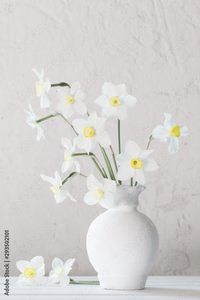 white narcissus in vase on wooden table