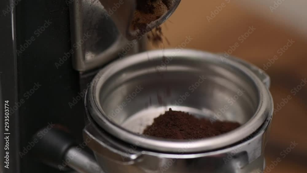 Slow motion close up of fresh coffee grinds from a burr grinder falling into a espresso machine portafilter. Slow motion close up of fresh coffee grinds from a burr grinder falling into a espresso machine portafilter.