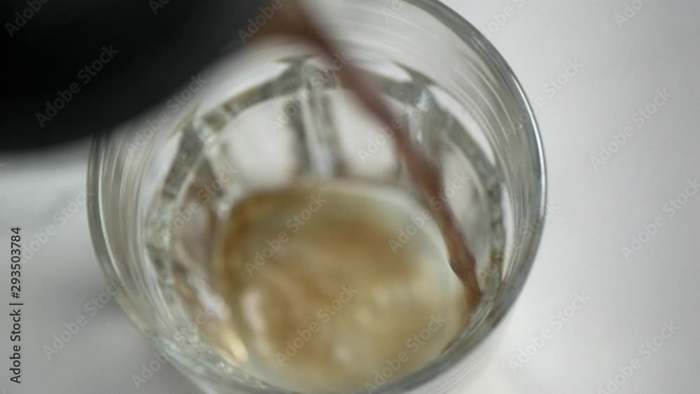Top down slow motion of coffee being poured into a clear glass. Top down slow motion of coffee being poured into a clear glass.